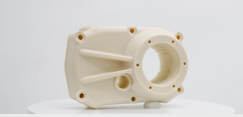 A 3D printed white mechanical part with multiple circular holes, a larger circular opening, and several reinforcing ribs.